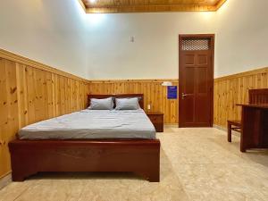a bedroom with a bed with wooden walls and a door at Nhà Nghỉ Thi Anh in Ấp Bia +13 photos