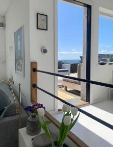 a living room with a couch and a table with flowers at Functionalist House Only 100 Steps To The Beach in Haderslev