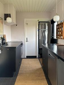 a kitchen with a black counter and a refrigerator at Functionalist House Only 100 Steps To The Beach in Haderslev