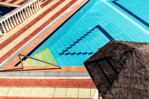 a swimming pool with an umbrella in front of it at Haroula Apartments in Sidari