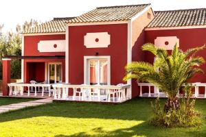 a red house with a palm tree in front of it at Haroula Apartments in Sidari