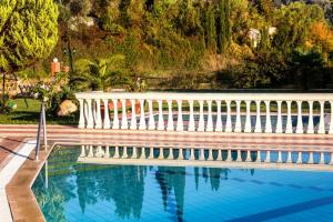 a swimming pool with a white fence and trees at Haroula Apartments in Sidari