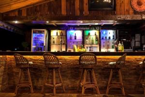a bar with three chairs in front of a bar at Haroula Apartments in Sidari