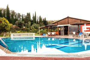 a large swimming pool with a house and a building at Haroula Apartments in Sidari