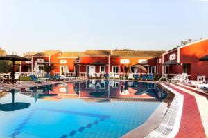 a pool at a resort with chairs and umbrellas at Haroula Apartments in Sidari