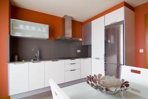 a kitchen with white cabinets and an orange wall at CANELAS CLASS con AMPLIAS TERRAZAS in Portonovo