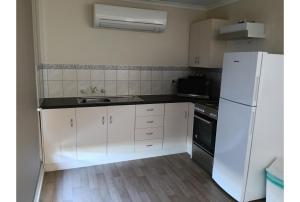 a kitchen with white cabinets and a white refrigerator at Discovery Parks - Roxby Downs in Roxby Downs
