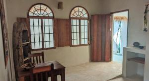 a living room with three windows and a table and chairs at Bahari Studio by Bora Pamoja Homes Pool, Solar Backup & 5 Min to Beach in Jambiani