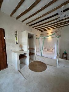 a room with a bed with a table and a table at Bahari Studio by Bora Pamoja Homes Pool, Solar Backup & 5 Min to Beach in Jambiani