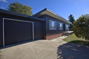 a black house with a garage at 2 Munyang Street in Jindabyne