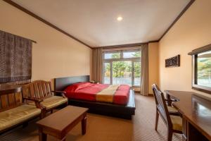 a bedroom with a bed and a chair and a window at Wellness Forest Nasu in Nasu