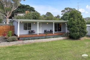 a small white house with a wooden deck at Between Waters Stay 3 Pay 2 Winter Special in Yanakie