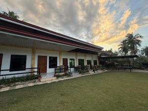 a building with benches and a grass field in front at CocoVille Guesthouse KUBO in Alegria