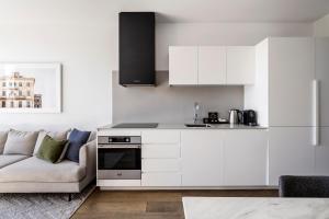 a kitchen with white cabinets and a couch at Tyrian Albert Park Lake in Melbourne