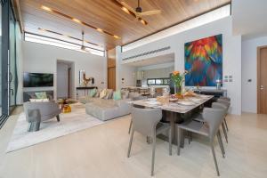 a dining room and living room with a table and chairs at Botanica Foresta 4BDR by Villacarte in Ban Phru Champa