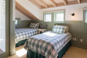 two beds in a room with green walls and windows at Valhalla The Loft (Oceanfront Hot tub) in Salt Spring Island +34 photos