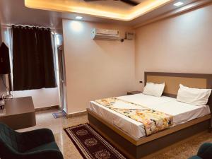 a hotel room with a bed and a chair at Regal Palace Hotel and Banquets in Patna