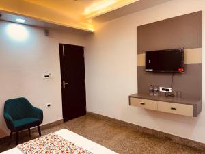 a room with a bed and a tv and a chair at Regal Palace Hotel and Banquets in Patna +39 photos