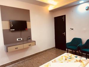 a room with two chairs and a tv on a wall at Regal Palace Hotel and Banquets in Patna