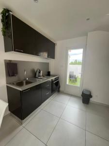 a kitchen with black cabinets and a sink and a window at Maison mitoyenne in Gignac-la-Nerthe