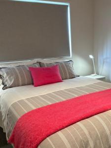 a bed with a red pillow on top of it at Aquila Nest in Whitianga +15 photos
