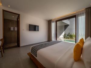 a bedroom with a large bed and a large window at Prawara Uluwatu in Uluwatu