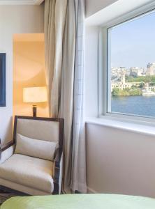 a bedroom with a window and a chair next to a bed at Kempinski Nile Hotel, Cairo in Cairo +215 photos