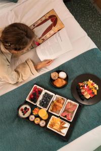 a woman laying on a bed with plates of food at Kempinski Nile Hotel, Cairo in Cairo