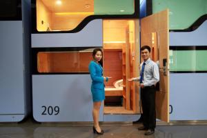 a man and a woman standing in front of a small bathroom at VATC Sleep Pod Terminal 1 in Noi Bai