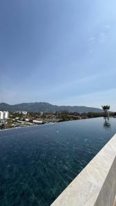 a large swimming pool with a view of a city at Skypark Celeste with stunning golf course view in Laguna Phuket