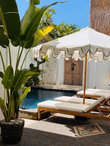 an umbrella and lounge chairs next to a swimming pool at Gypsea Rest Private Villa in Nusa Lembongan