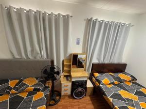 a bedroom with two beds and a window with curtains at Breena & Dhanie's Haven I in Labac