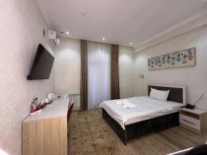 a bedroom with a bed and a desk in it at STATUS HOTEL in Qarshi
