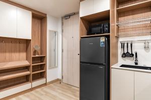 a kitchen with a black refrigerator and wooden cabinets at Skypark by Villacarte in Laguna Phuket