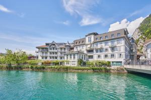 a row of buildings next to a body of water at City Center Apartment with Mountain View in Interlaken