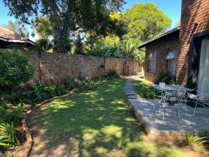a yard with a table and chairs next to a brick wall at Dragonfly in Boksburg
