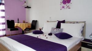 a bedroom with a large bed with purple pillows and a table at SARITA Apartments in Makarska