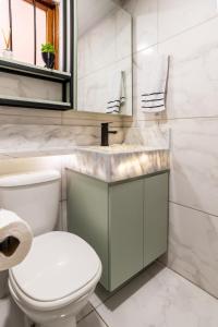 a bathroom with a white toilet and a sink at Studio c Piscina, AC e Café Novo Hamburgo in Novo Hamburgo +22 photos