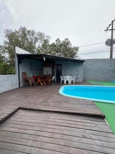 a deck with a pool and a table and a house at Studio c Piscina, AC e Café Novo Hamburgo in Novo Hamburgo