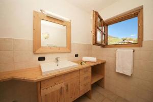 ein Badezimmer mit Waschbecken, Spiegel und Fenster in der Unterkunft Sponda Ski in- Ski out 50m - Happy Rentals in Livigno