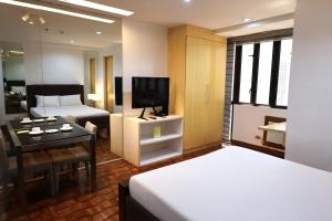 a bedroom with a bed and a desk and a television at Prince Plaza II Condotel in Manila
