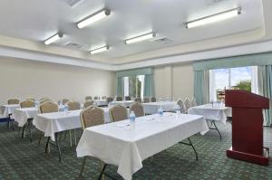 a conference room with white tables and chairs and a podium at Ramada by Wyndham South Waco in Hewitt