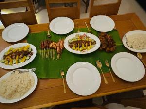 a wooden table with plates of food and forks and dishes at Jaffna City Palace Hotel in Jaffna