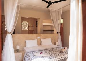 a bedroom with a large bed with white curtains at Little Maua - Stylish Private Hideaway on Galu Beach in Galu