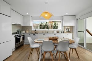 a kitchen with a wooden table and white chairs at Mellow mountains, boutique beach house in Portarlington