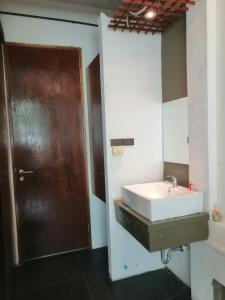 a bathroom with a sink and a wooden door at 75 StangStay & Cafe de Art in Ka Rorn