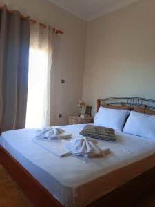 a bedroom with a bed with white sheets and a window at Cozy country house in Preveza