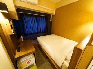 a small room with a bed and a table at Super Hotel Lohas Ikebukuro-Eki Kitaguchi in Tokyo
