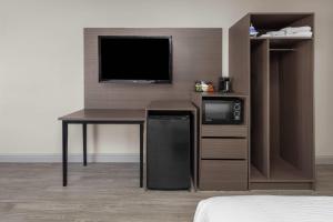 a room with a desk with a tv and a microwave at Angel Inn Near IMAX, a Travelodge by Wyndham in Branson