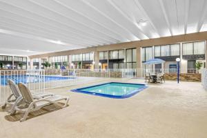 a swimming pool in a building with two chairs and avisor at Quality Inn & Suites in Grayling